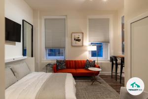 a bedroom with a bed and a red couch and a table at Inner Harbor's Best Luxury Furnished Apartments apts in Baltimore