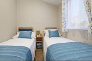 two beds in a room with blue and white at Lancaster Views, Luxury 2022 home with Hot Tub in Tattershall +8 photos