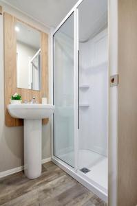 ein Bad mit einem Waschbecken und einer Glasdusche in der Unterkunft Lancaster Views, Luxury 2022 home with Hot Tub in Tattershall