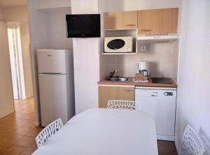 Résidence Graziella Appartement 627 في خوان ليس بينس: مطبخ صغير مع ثلاجة بيضاء ومغسلة