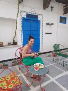 a woman sitting in a chair in front of a blue door at Madan Mohan Villas (A Haritage Haveli Home Stay) in Udaipur
