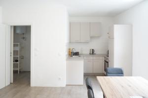 a white kitchen with a wooden table and chairs at Chill & Relax Apartments Purbach in Purbach am Neusiedlersee