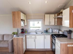 a small kitchen with white cabinets and a couch at Caravan Skegness 8 Berth in Skegness