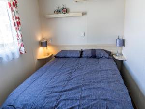 a bedroom with a bed with blue sheets and two lamps at Caravan Skegness 8 Berth in Skegness