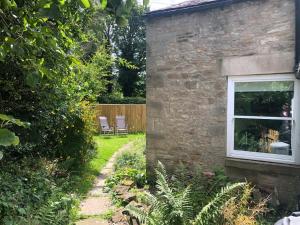 um jardim com uma casa de pedra e uma janela em Stunning Studio in Corbridge, Northumberland em Corbridge