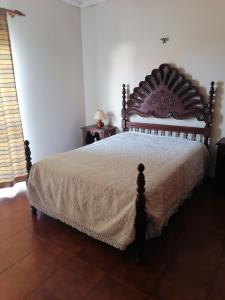 a bedroom with a large bed with a wooden headboard at Propriedade dos Seixos in Moledo