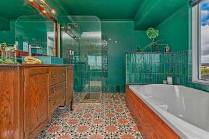 a green bathroom with a tub and a shower at Arcadia Beachfront Retreat in Mandurah