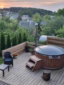 a hot tub on a wooden deck with a bench and a chair at ODM&A apartment in Vilnius