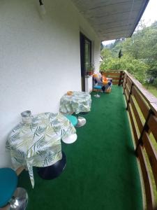 a balcony with two tables on a green floor at The RiverSide Chill Hostel in Zgornje Gorje