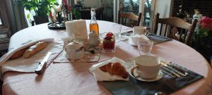 une table avec un tissu de table, du pain et des tasses à café dans l'établissement Le Clos des Roses, à Parçay-les-Pins