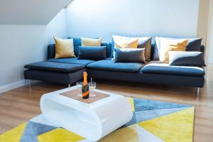 Sala de estar con sofá azul y botella de vino en Apartamenty Wielbarska, en Szczytno