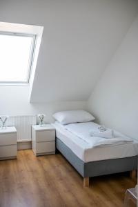 a white bedroom with a bed and a window at Apartamenty Wielbarska in Szczytno