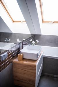 a bathroom with a white sink and a skylight at Apartamenty Wielbarska in Szczytno