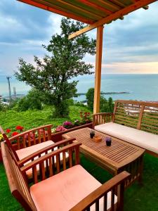 a wooden table and chairs on a patio with the ocean at Manzara dağevi in Rize