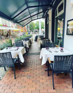 un restaurante con mesas blancas y sillas en un patio de ladrillo en Ratshotel, en Haltern