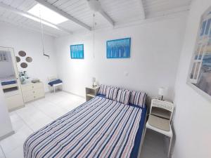 a white bedroom with a bed and a chair at Brisa Marina - Vista Golf 2 - WiFi - swimming pool in Caleta De Fuste