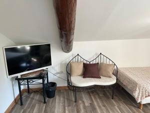 Pokój z krzesłem, telewizorem i łóżkiem w obiekcie Auberge les Galets w mieście Peyruis