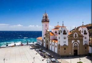 a large building with a clock tower next to the ocean at Balcón Atlantida in Candelaria