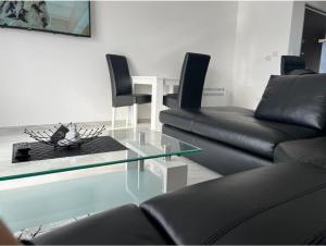 a living room with black leather furniture and a glass table at Apartman Sara Tivat in Tivat