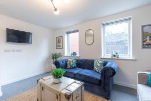 a living room with a blue couch and a table at Modern Four Bedroom Four Bathroom Home in Cheltenham