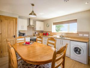 a kitchen with a wooden table with chairs and a sink at Sheaf Dale in Portmahomack