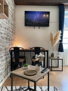a living room with a table and a tv on a wall at Escapade Moretaine - Cosy Studio in Moret-sur-Loing