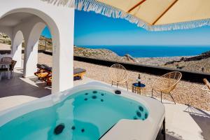 un patio con bañera de hidromasaje y vistas al océano en Acria Villas en Pirgos