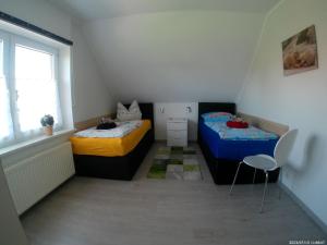 two beds in a small room with a window at Ferienwohnnung Kathrin in Wremen