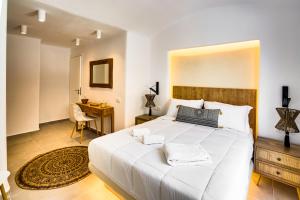 a bedroom with a large white bed and a desk at Acria Villas in Pyrgos