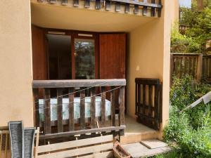 une terrasse couverte d'une maison avec une porte en bois dans l'établissement T3 au calme rez de jardin station LA COLMIANE, à Valdeblore