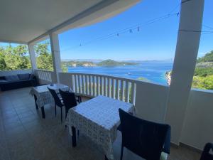 a balcony with tables and chairs and a view of the water at Guest House Ruža in Sobra