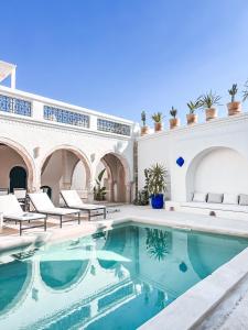 a pool in the courtyard of a house with chairs at Dar Naël in Houmt Souk