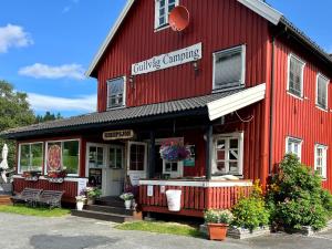 ein rotes Gebäude mit einer Bank außerhalb des Gebäudes in der Unterkunft Gullvåg Camping Nyberg in Soknedal