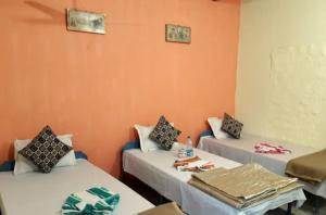 2 Betten in einem Zimmer mit orangefarbenen Wänden in der Unterkunft Superinn home stay& guest house in Agra