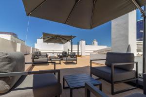 een patio met stoelen en tafels en een parasol bij Allo Apartments San Roque 1ºA in Cádiz