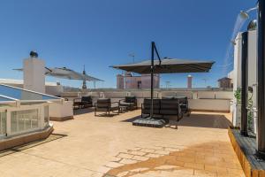 een patio met stoelen en een parasol op een dak bij Allo Apartments San Roque 1ºA in Cádiz