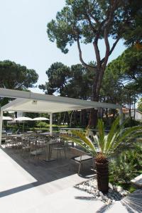 un patio con tavoli e sedie sotto un baldacchino bianco di Hotel Bella Venezia Mare a Lignano Sabbiadoro