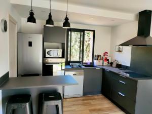 eine Küche mit schwarzen und weißen Arbeitsflächen und Geräten in der Unterkunft Jardin et 2 chambres centre St Florent in Saint-Florent
