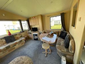 a living room with a couch and a table in a caravan at Peaceful holiday home on a park on the Kent Coast in St Margarets at Cliff