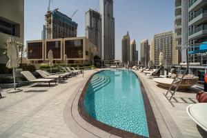 einen großen Pool mit Liegestühlen und Gebäuden in der Unterkunft Spectacular Views of Burj & Fountain - 2 BR in Dubai