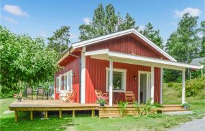 a red cottage with a wooden porch and a deck at Awesome Home In Malmkping With Kitchen in Malmköping