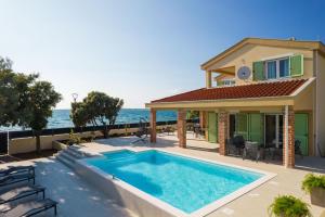 a house with a swimming pool next to the ocean at Exclusive luxury Villa with glorious sea view - by TA Leut Agency in Privlaka