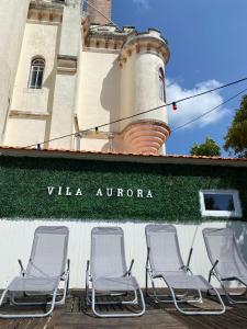 um grupo de cadeiras sentadas fora de um edifício com um farol em Vila Aurora no Luso