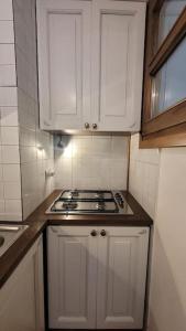 eine kleine Küche mit weißen Schränken und einem Herd in der Unterkunft Presolana Suite in Love casa vacanza in Castione della Presolana