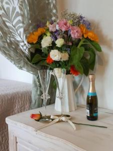 eine Vase Blumen auf einem Tisch neben einer Flasche in der Unterkunft Presolana Suite in Love casa vacanza in Castione della Presolana