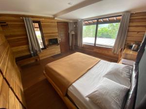 ein Schlafzimmer mit einem großen Bett in einem Holzzimmer in der Unterkunft Shine River in Ciwidey