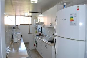 cocina blanca con nevera y fregadero en Apartamento Altos del Mar, en Antofagasta