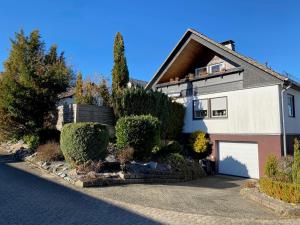 a white house with a garage and some bushes at Ferienwohnung mit Loggia in Warstein