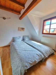 1 dormitorio con 1 cama con edredón azul y ventana en LE SCHMOUTZ: Charmant duplex entre Colmar et Mulhouse (1-4 pers), en Ensisheim