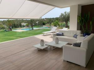 ein Wohnzimmer mit weißen Möbeln und einem Pool in der Unterkunft 3-bed room appartement at Las Colinas Golf & Country Club in Orihuela